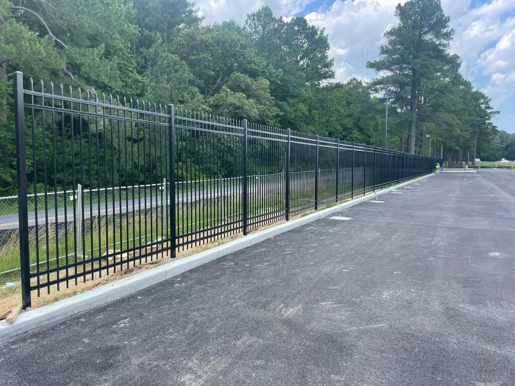an empty parking lot with a black fence