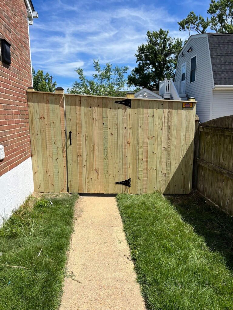 a wooden gate in the grass next to a house
