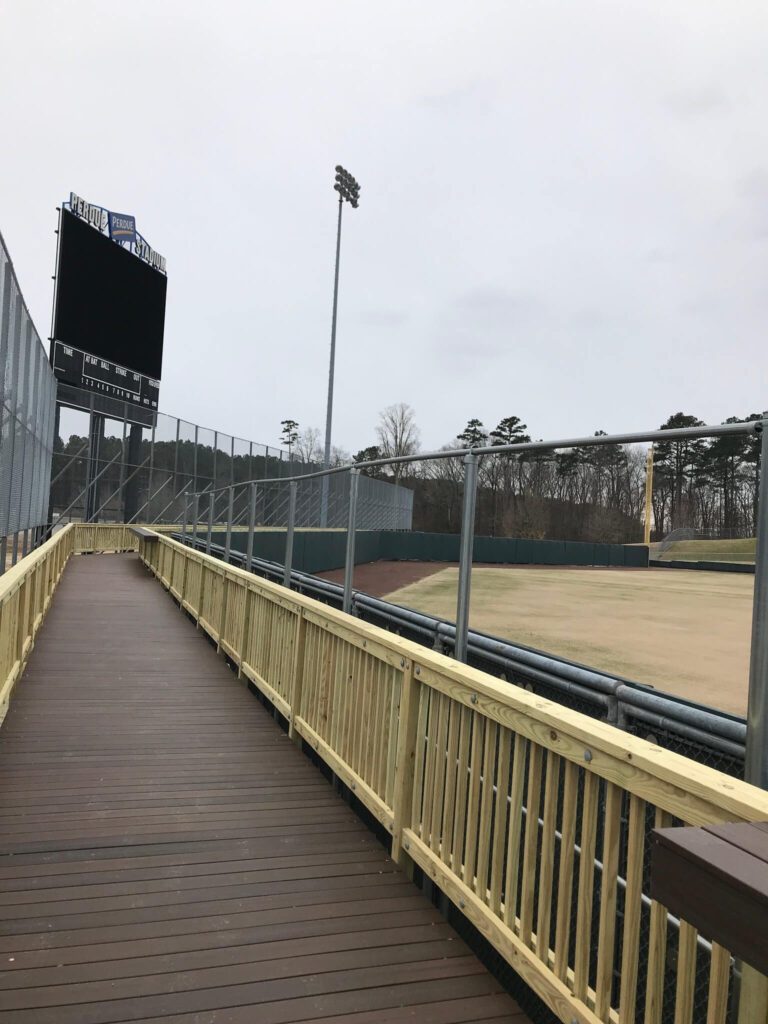 a wooden walkway leading to a baseball field